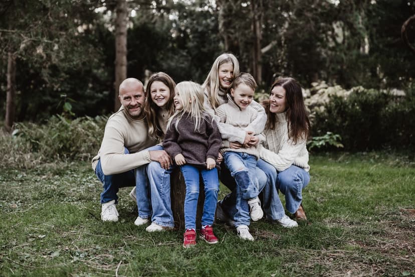 Familie sitzt auf einem Baumstamm